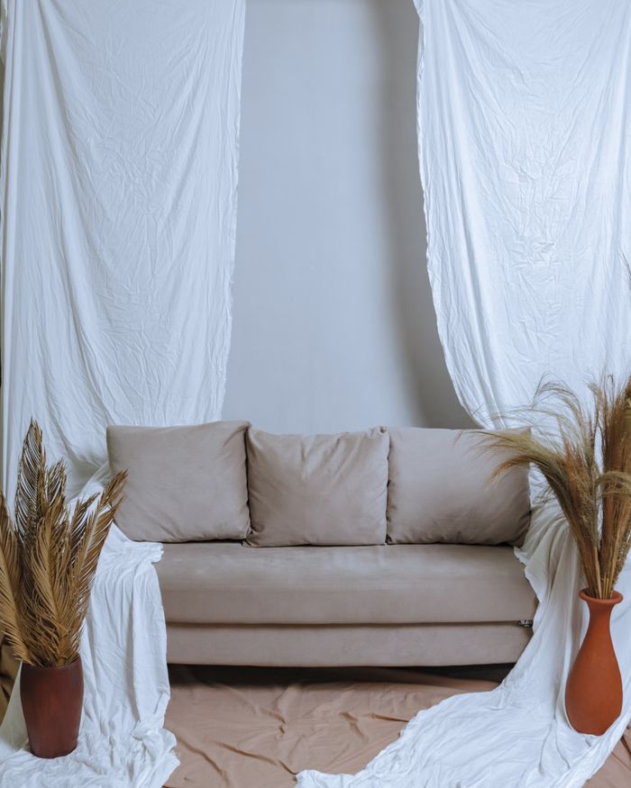 get-in-touch Stylish interior featuring a beige couch with decorative drapes and potted plants.