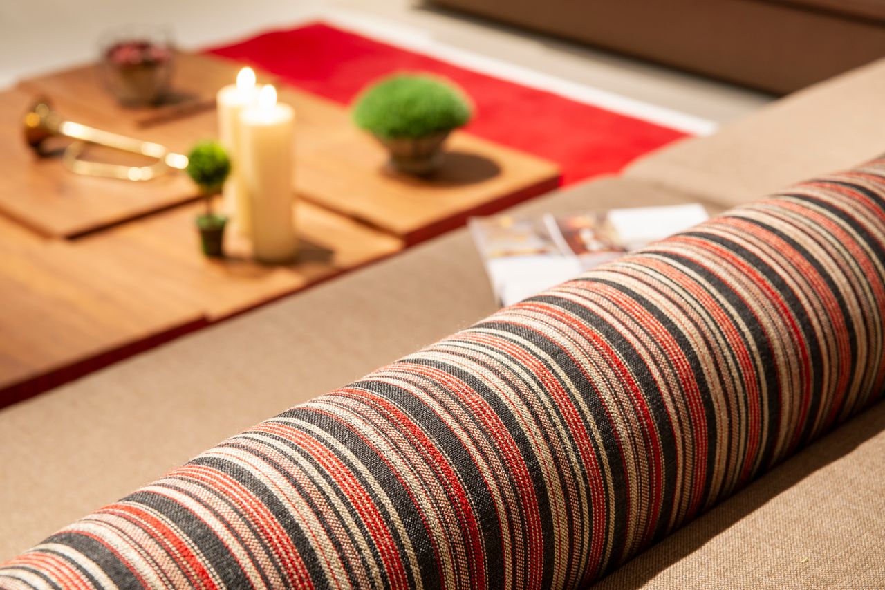 why-choose-us A close-up view of a striped sofa with candles and decor in a warm, inviting setting.