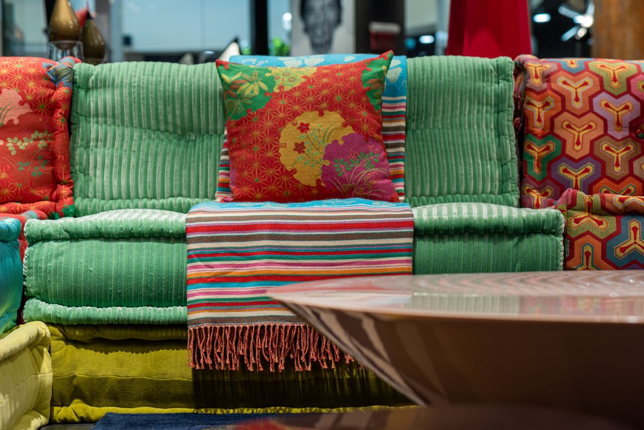 Bright soft couch made with velvet fabric near glossy round table in stylish modern apartment